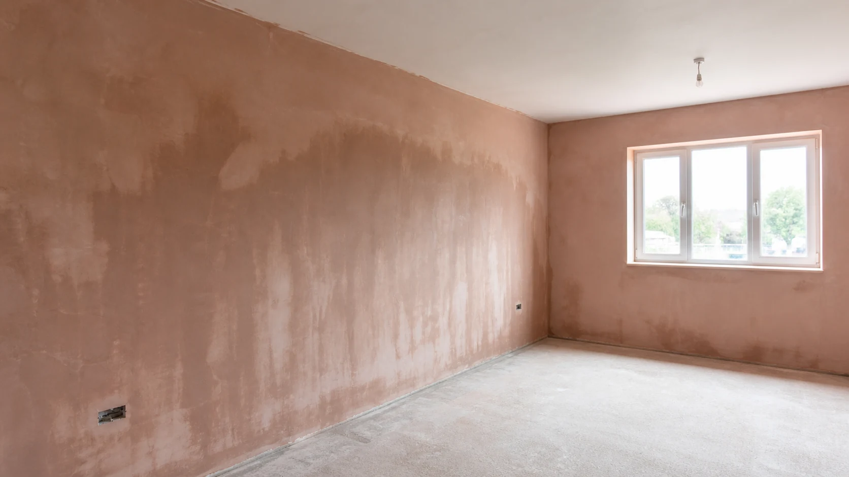 A freshly plastered new-build room with drying pink plaster walls